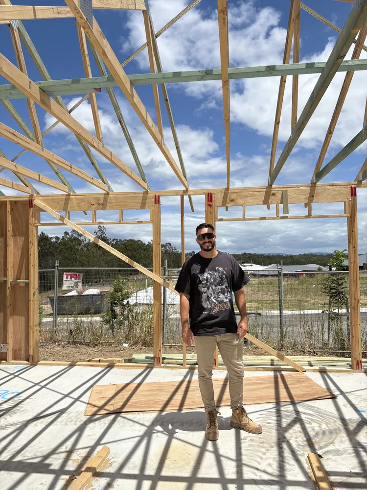 Jay standing in the frame of a house under construction